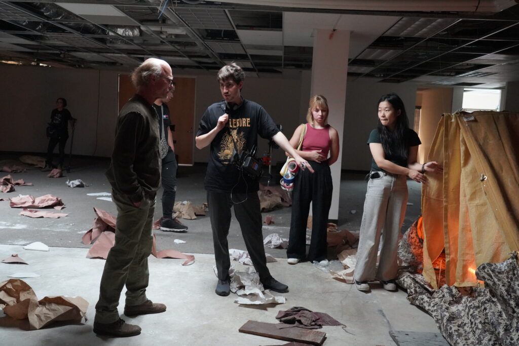 Ed Harris and some members of the crew for "Concrete" on set talking with one another.