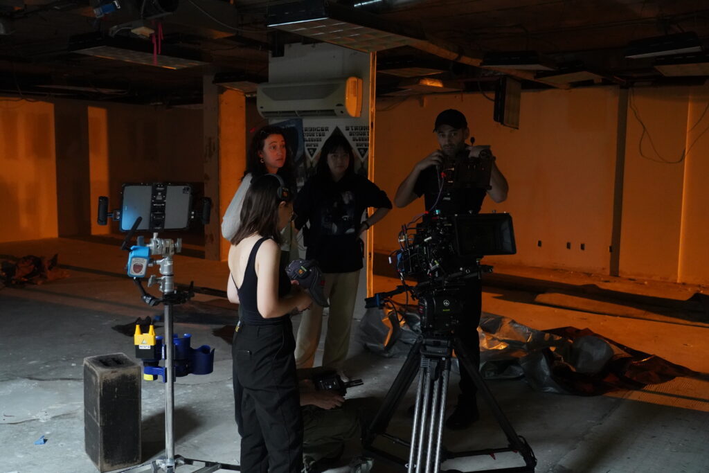 Four members of the crew of the film "Concrete" surrounding a camera on set.